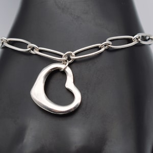 May include: A silver chain bracelet with a large open heart charm.