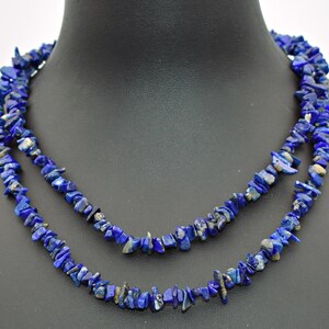 May include: A double-strand necklace composed of irregular, tumbled lapis lazuli stone chips. The deep blue stones feature natural variations and occasional flecks of gold-coloured pyrite, strung together to create a textured, layered appearance.