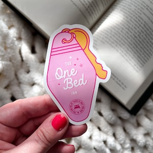 Puede incluir: Pegatina rosa en forma de llave con el texto "THE One Bed INN" y un peque&ntilde;o c&iacute;rculo con un icono de cama y el texto "THERE IS ONLY ONE BED YOU HAD ME AT"