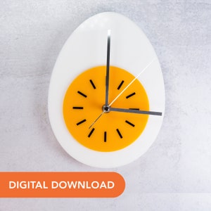 May include: A wall clock shaped like a hard-boiled egg, with a white eggshell and a yellow yolk. The clock hands are black, and the hour markers are black dashes. The words "DIGITAL DOWNLOAD" are in an orange rectangle at the bottom.