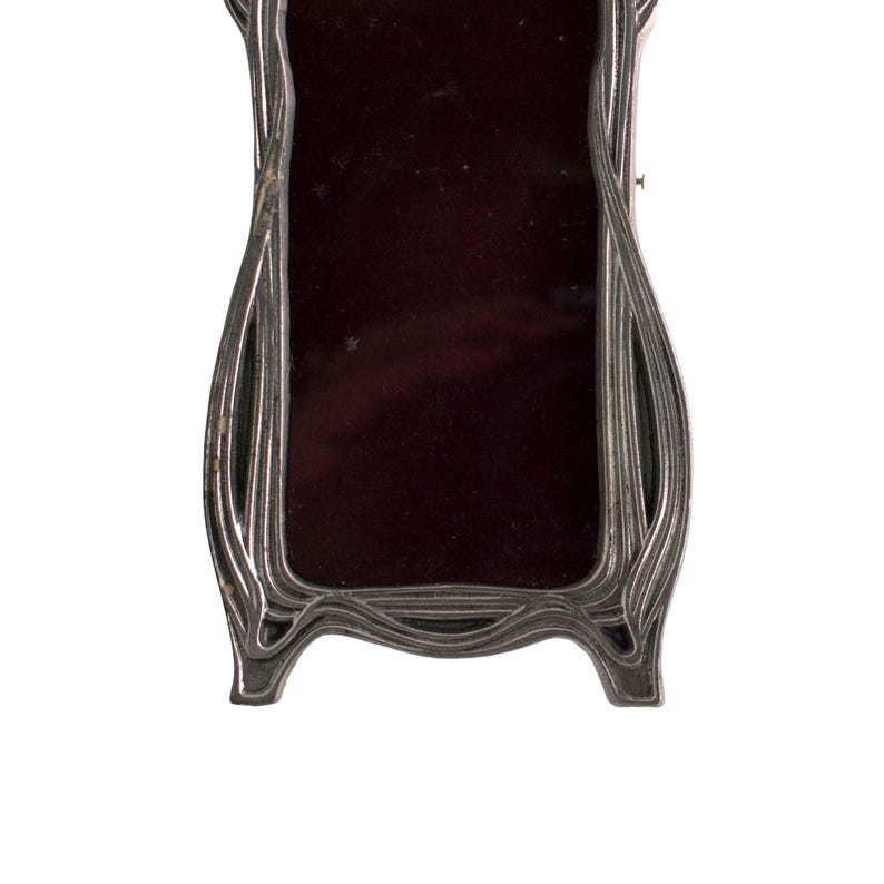 May include: A silver-colored, ornate picture frame with a dark red velvet interior. The frame has a unique, flowing design.