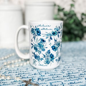 May include: White ceramic mug with a blue and white floral pattern. The mug has the word "alleluia" written on it three times.