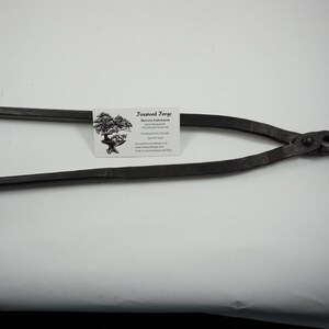 May include: Black metal bonsai pliers with a rounded handle and a small, pointed jaw. The pliers are on a white surface with a business card that reads "Bonsai Forge, Steven Farese, Bonsai, Florida, www.bonsaiforge.com".