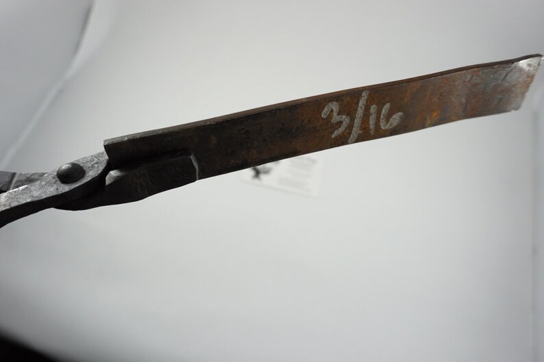 May include: Close-up of a rusty metal tool with a handle and a blade. The blade is marked with the fraction "3/16".