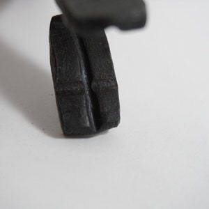 May include: A close-up of a black rubber wheel with a textured surface. The wheel is designed for a toy or model.