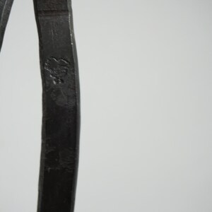 May include: Close-up of a pair of black metal calipers. The calipers are made of a single piece of metal and have a smooth, polished finish.
