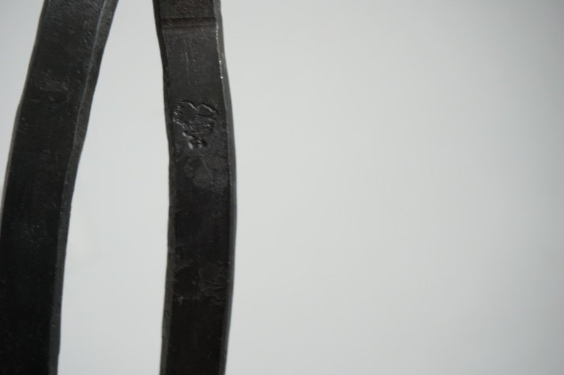 May include: Close-up of a pair of black metal calipers. The calipers are made of a single piece of metal and have a smooth, polished finish.