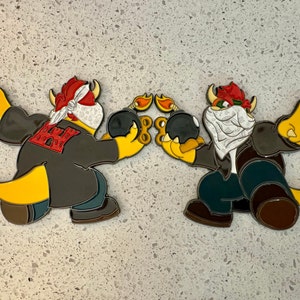 May include: Two cartoon character figures, each holding a black bomb with a lit fuse. The figures have yellow hands and feet, red hair, and are wearing jackets. One figure has a red bandana and the other has a white bandana.