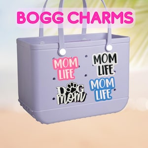 May include: A lavender tote bag with four charms that say "Mom Life" in different colors and fonts. One charm has a paw print and says "Dog Mom".