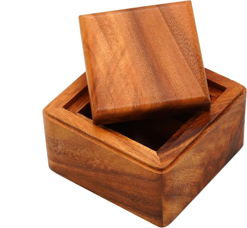 Op de afbeelding: Een houten kist met een iets geopende deksel, die de binnenkant laat zien. De kist is gemaakt van warm getint hout, met zichtbare nerfpatronen. Het vierkante deksel past netjes bovenop. De kist is waarschijnlijk voor opslag of weergave.