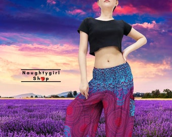 May include: A woman wearing a black crop top and pink and blue patterned pants with a floral design. The pants have a wide leg and a loose fit. The woman is standing in front of a field of purple flowers.