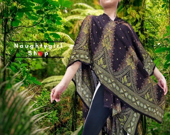 May include: A black and green patterned poncho with a paisley design. The poncho is worn over black leggings with a white stripe down the side.