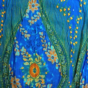 May include: A blue fabric with a floral pattern. The flowers are orange, yellow, and green. The fabric has a paisley-like design.