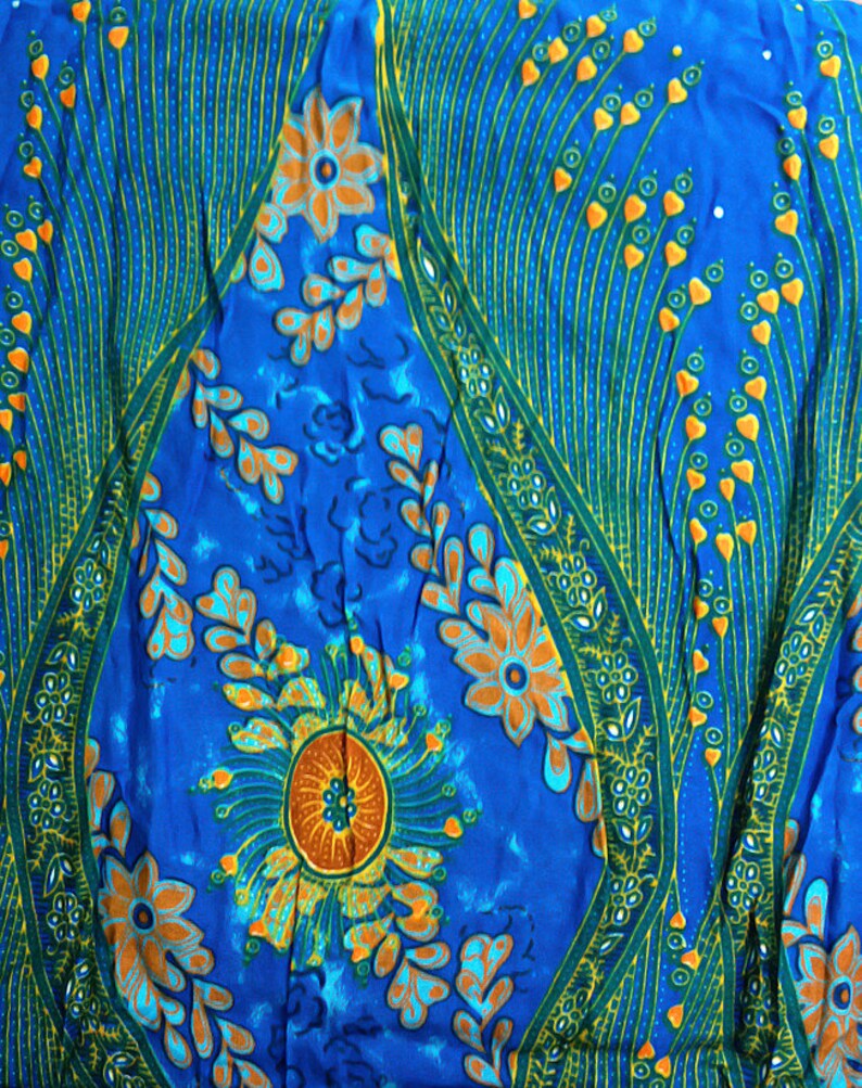 May include: A blue fabric with a floral pattern. The flowers are orange, yellow, and green. The fabric has a paisley-like design.