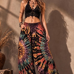 May include: A black lace halter top paired with vibrant tie-dye pants. The pants feature a colorful burst pattern in shades of orange, purple, yellow, and blue. The outfit is a bohemian style, perfect for a casual, yet stylish look.