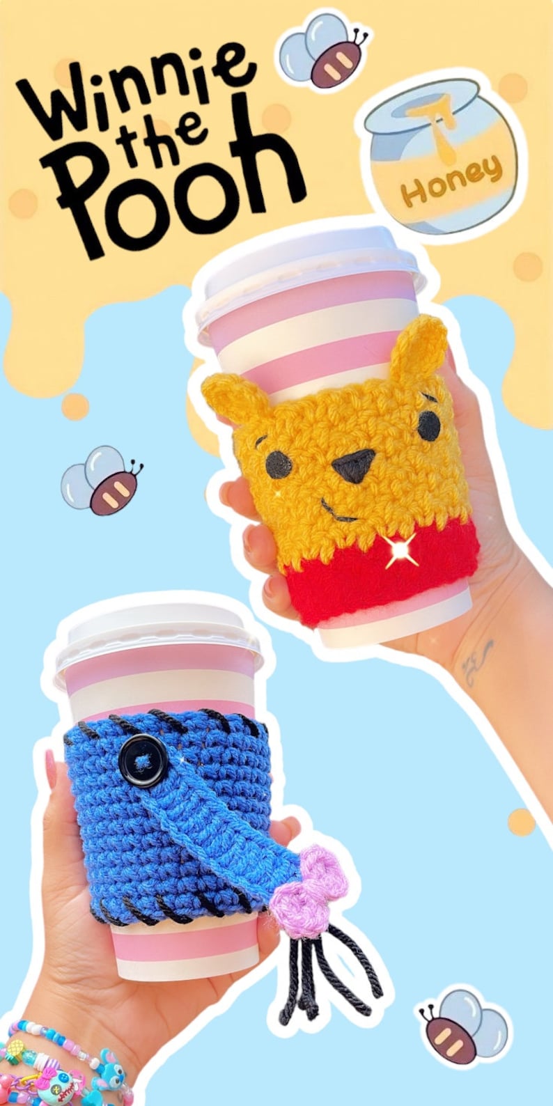 May include: Two paper coffee cups with crocheted cozies. One cozy is yellow and red, resembling Winnie the Pooh. The other is blue with a black button and a pink bow. The background has Winnie the Pooh themed graphics.