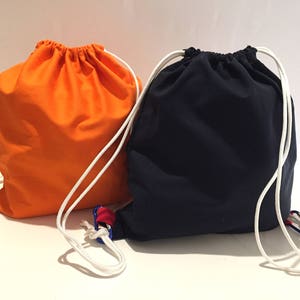 May include: Two drawstring bags, one orange and one black, with white drawstrings and blue and red accents.
