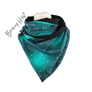 Puede incluir: Una bufanda infinita de color turquesa y negro con un estampado floral blanco. La bufanda está hecha de una tela suave y cómoda y es perfecta para mantenerse caliente en invierno.