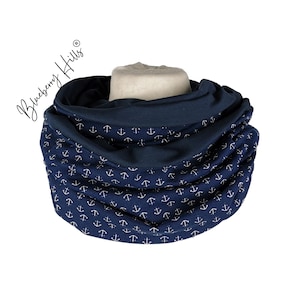 Peut inclure: Une écharpe infinie bleu marine avec un motif d'ancre blanche. L'écharpe est faite d'un tissu doux et confortable et est parfaite pour se tenir au chaud en hiver.