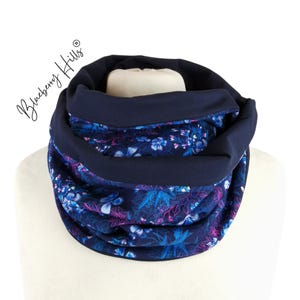 Könnte beinhalten: Ein marineblauer Infinity-Schal mit einem Blumendruck in Blautönen, Rosa und Weiß. Der Schal ist aus einem weichen, komfortablen Stoff gefertigt und perfekt, um sich im Winter warm zu halten.