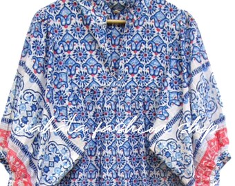 Puede incluir: Un vestido midi con un estampado floral repetitivo en azul y rosa sobre una base blanca. La prenda cuenta con un cuello alzado con volantes, escote en V y mangas voluminosas de tres cuartos con puños ribeteados en color rosa.