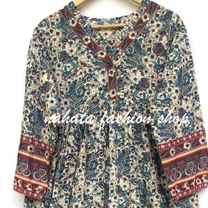 Puede incluir: Vestido de manga larga con estampado floral y cachemir en crema, verde azulado y burdeos. El vestido presenta un escote en V con ribete burdeos, mangas tres cuartos y cintura fruncida. El texto "mahata fashion shop" es visible.