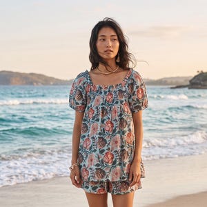 May include: A light blue two-piece set consisting of a short-sleeved blouse with a square neckline and matching shorts, both featuring a repeating floral pattern in shades of red, dark brown, and green with a soft, gathered texture.