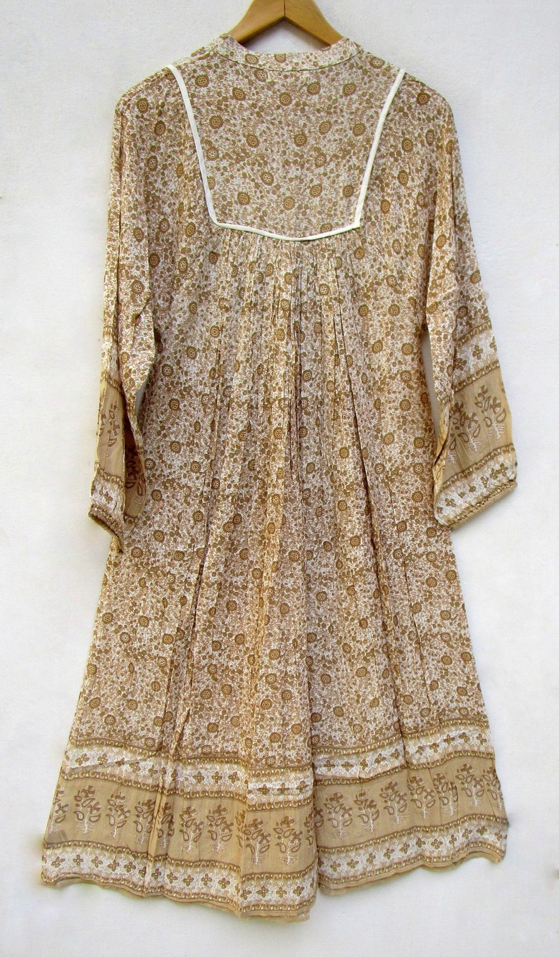 May include: A white cotton dress with a brown floral print and white trim. The dress has long sleeves and a gathered waist.
