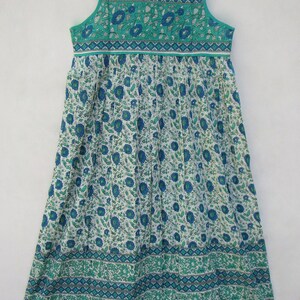 K&ouml;nnte beinhalten: Ein &auml;rmelloses Maxikleid mit einem Blumenmuster in Blau- und Gr&uuml;nt&ouml;nen. Das Kleid hat einen gerafften Rock und ein tailliertes Oberteil mit einem kontrastierenden Besatz.