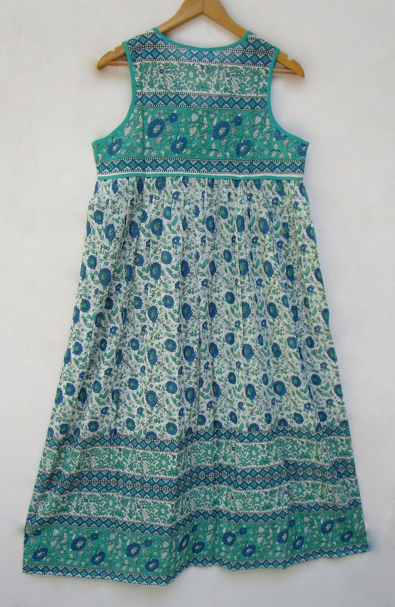 K&ouml;nnte beinhalten: Ein &auml;rmelloses Maxikleid mit einem Blumenmuster in Blau- und Gr&uuml;nt&ouml;nen. Das Kleid hat einen gerafften Rock und ein tailliertes Oberteil mit einem kontrastierenden Besatz.