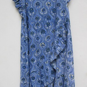 May include: A blue and white printed cotton dress with a ruffled neckline and sleeves. The dress has a loose fit and a flowing skirt.