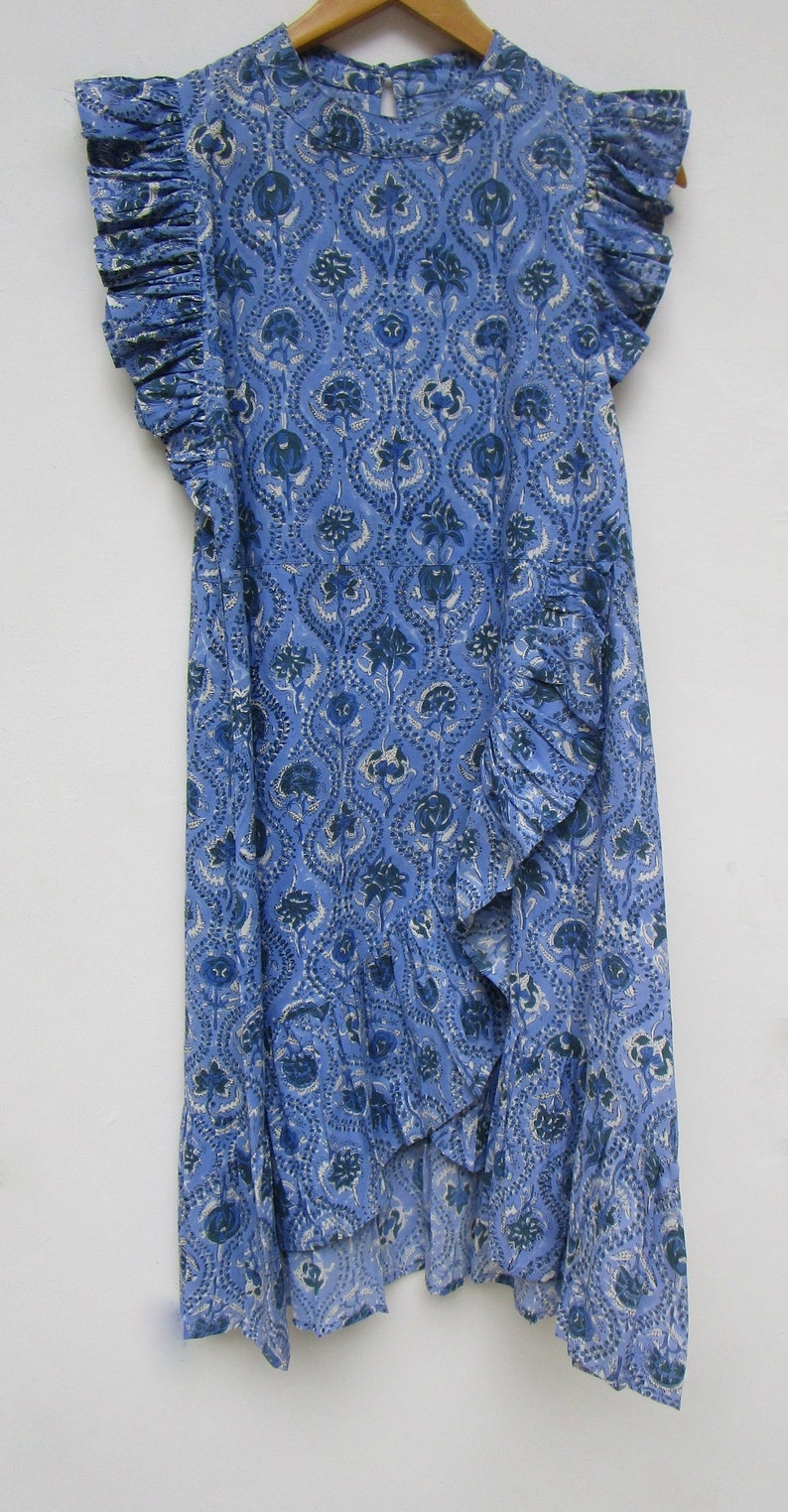 May include: A blue and white printed cotton dress with a ruffled neckline and sleeves. The dress has a loose fit and a flowing skirt.