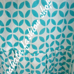 May include: White fabric with a teal blue geometric pattern of overlapping leaf shapes. The fabric has a gathered look at the bottom.