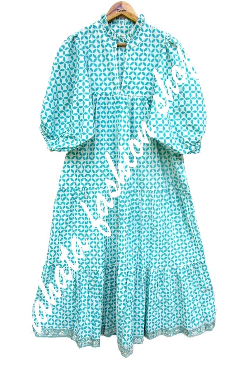 May include: A turquoise blue and white patterned dress with a ruffled neckline and puff sleeves. The dress has a tiered skirt and a white trim around the bottom.