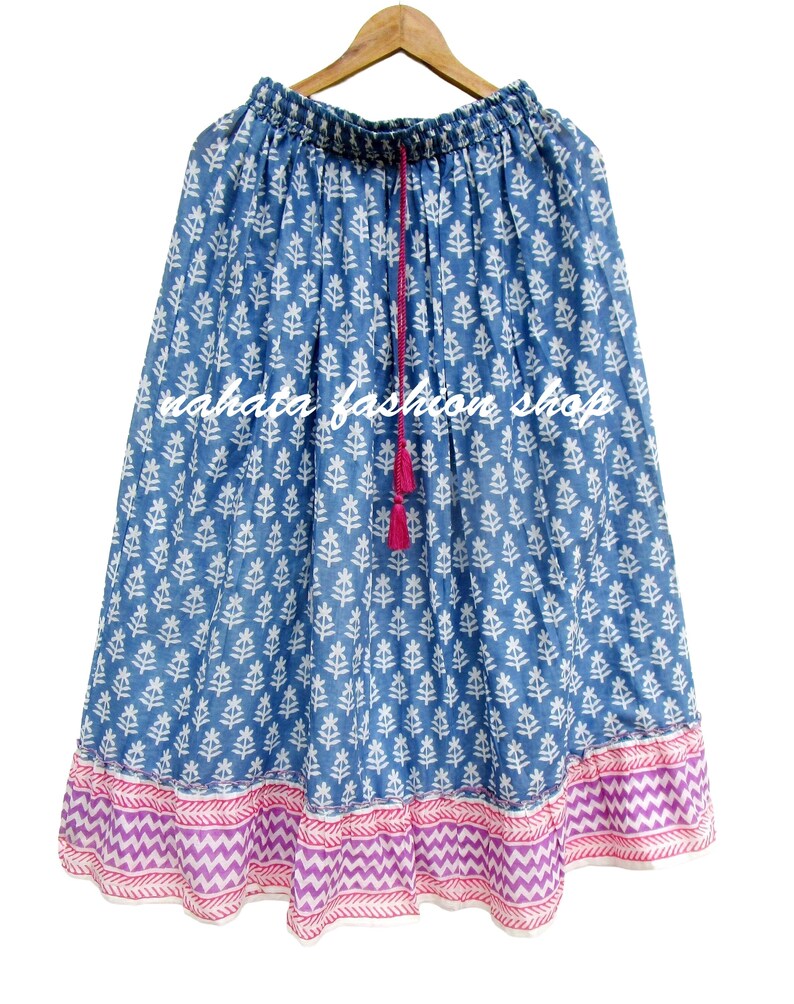 May include: A blue skirt with a white leaf pattern and a pink and purple zigzag border. The skirt has a drawstring waist with a pink tassel. The text "nahata fashion shop" is printed on the skirt.