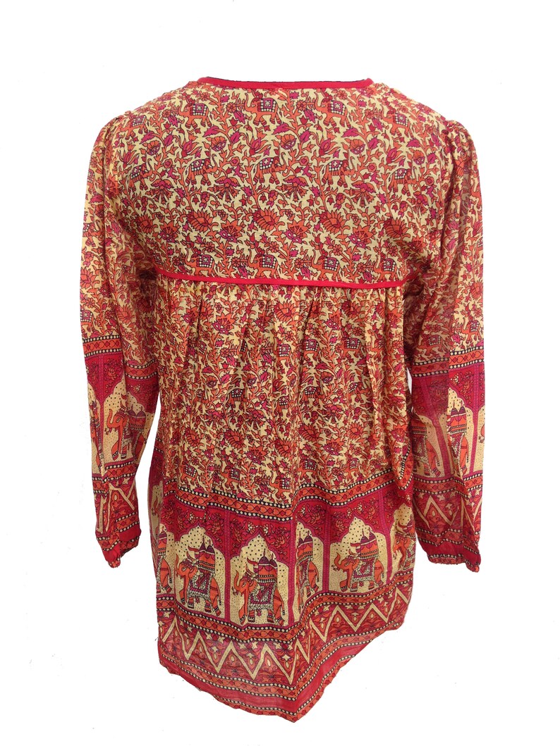 May include: A long-sleeved, red and cream colored tunic with an elephant print. The tunic has a V-neck and a gathered waist.
