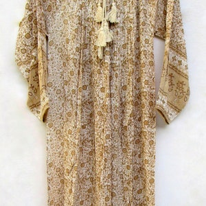 May include: A long-sleeved, white and brown floral print dress with a white lace trim around the neckline. The dress has a tie at the neckline with tassels and a gathered skirt.