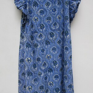 May include: A blue cotton dress with a floral print and ruffled sleeves. The dress has a round neckline and a gathered skirt.