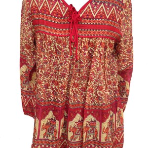 May include: A red and cream long-sleeved blouse with an elephant print and a tie at the neckline.