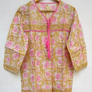 May include: A yellow and pink floral print cotton tunic top with a tie at the neckline and 3/4 sleeves.