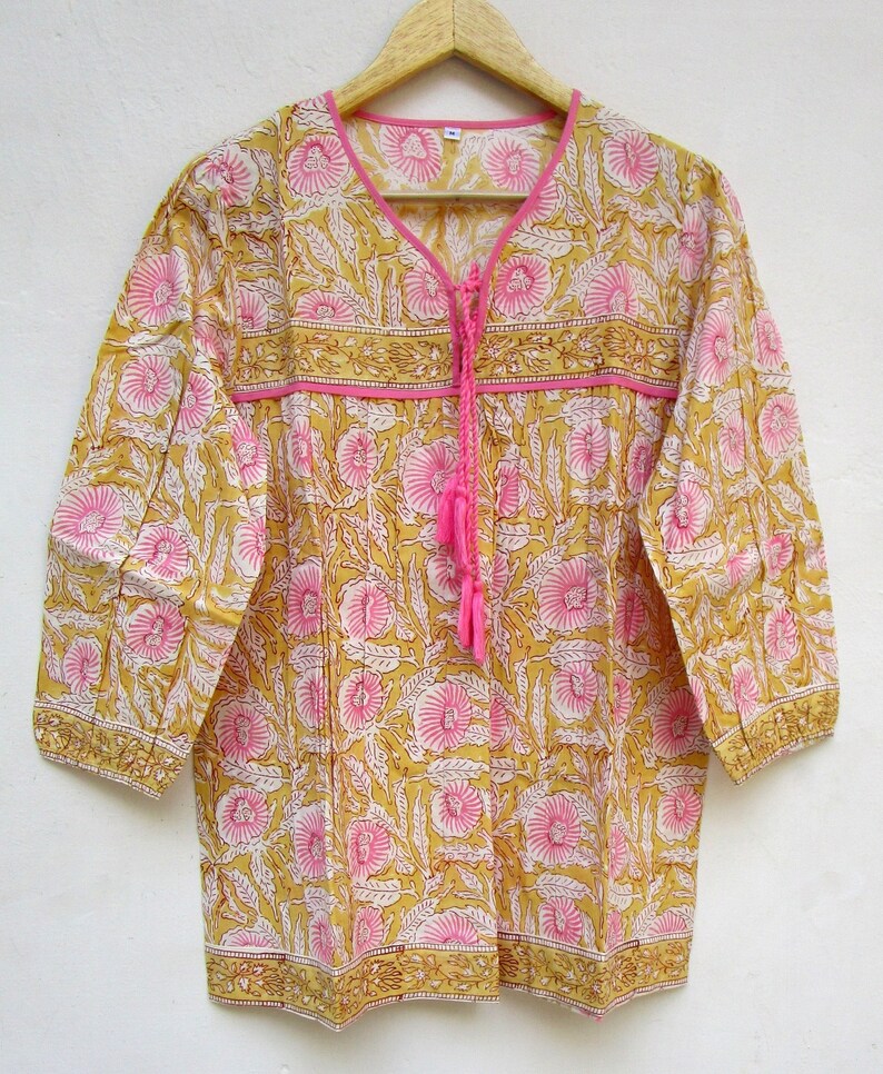 May include: A yellow and pink floral print cotton tunic top with a tie at the neckline and 3/4 sleeves.
