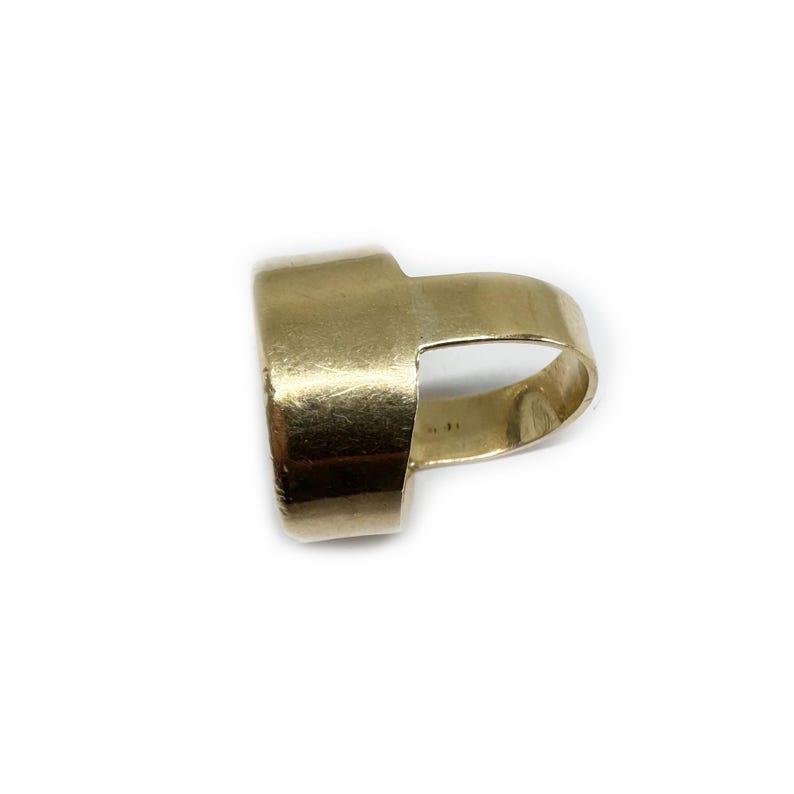 May include: A gold ring with a wide band and a unique open design. The ring is made of a smooth, polished metal.