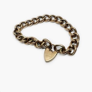 May include: A gold chain bracelet with a heart-shaped charm. The charm has the inscription "9ct" on it.