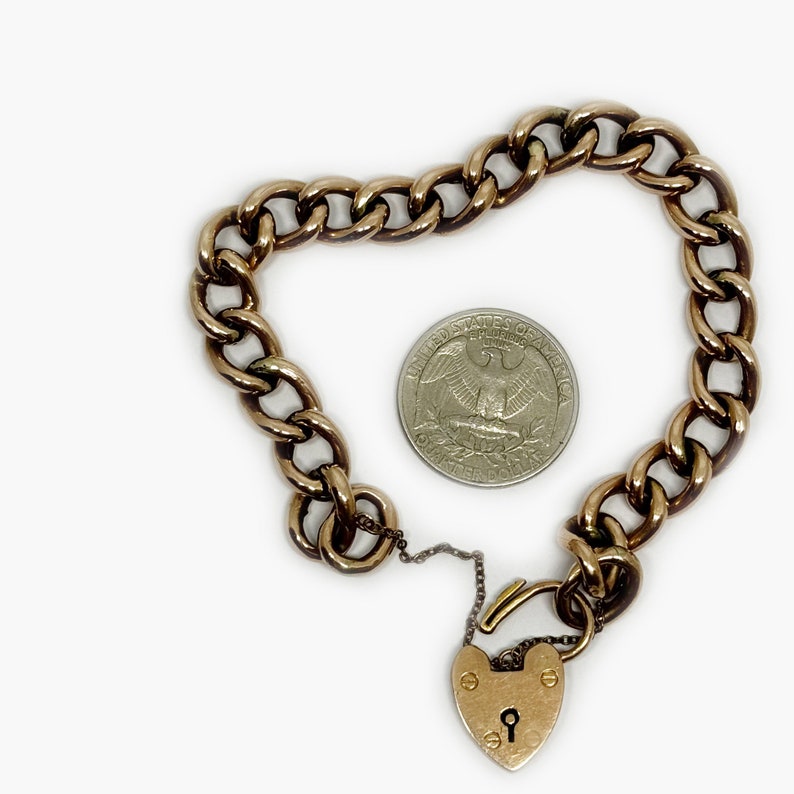 May include: A gold chain bracelet with a heart-shaped padlock charm. The bracelet is about the size of a quarter.