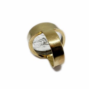 May include: A gold ring with a clear stone set in the center. The stone has a design etched into it.