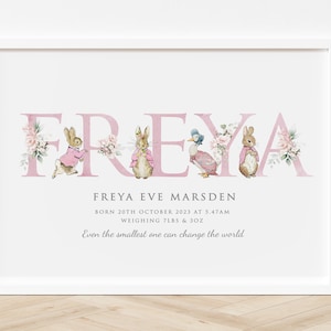 Può includere: Una stampa incorniciata con il nome "FREYA" in rosa, decorata con elementi floreali e illustrazioni dei personaggi di Peter Rabbit. La stampa include il nome del bambino, la data di nascita, l'ora e il peso (3,2 kg), con la citazione "Even the smallest one can change the world."