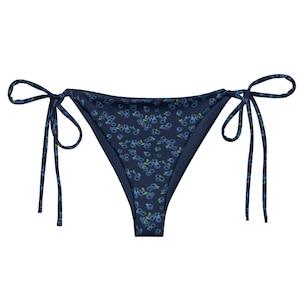 May include: Navy blue bikini bottom with a floral print. The bikini bottom has adjustable ties on the sides.