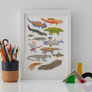 May include: A white framed print featuring a colorful illustration of various aquatic and amphibian creatures, including a dragonfly, a fish, a salamander, and a centipede. The print is titled "Jamie Sawyer".