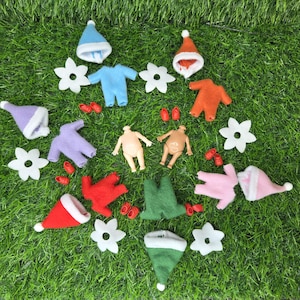 May include: A collection of miniature felt doll clothes and accessories, including hats, onesies, shoes, and flower-shaped decorations. The items are in various colors such as blue, orange, green, red, pink, and purple. The items are arranged on a green surface.