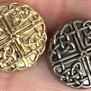 May include: Two round buttons featuring a Celtic knot design. One button is gold and the other is silver.